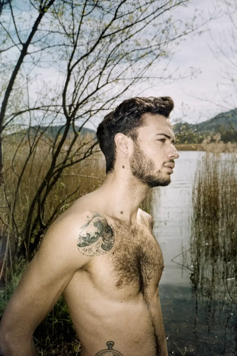 Portrait d'un homme torse nu barbu en profil, éclairé par une lumière naturelle diffuse, dans un style photographique analogique contemplatif au bord d'un lac
