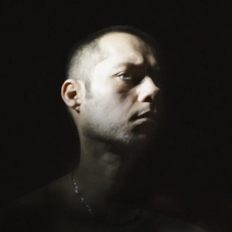 Portrait d'un homme au crâne rasé, éclairé par un chiaroscuro dramatique sur fond noir, dans un style baroque contemporain aux accents cinématographiques