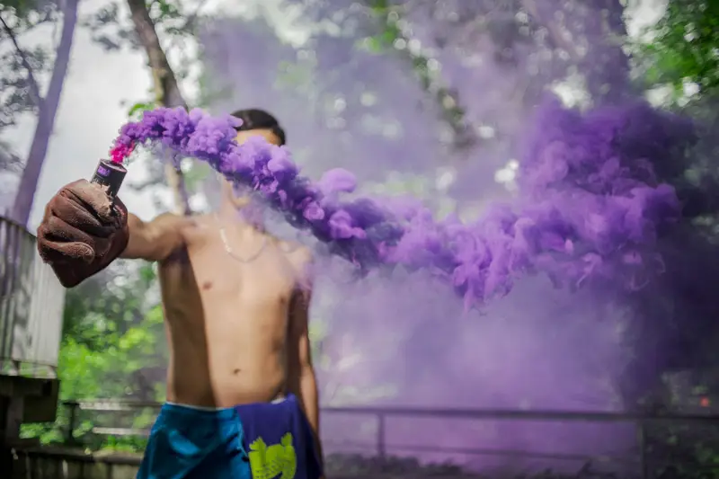 Danseur en équilibre acrobatique sur une main, casquette à motifs colorés, fond noir, photographie de mouvement